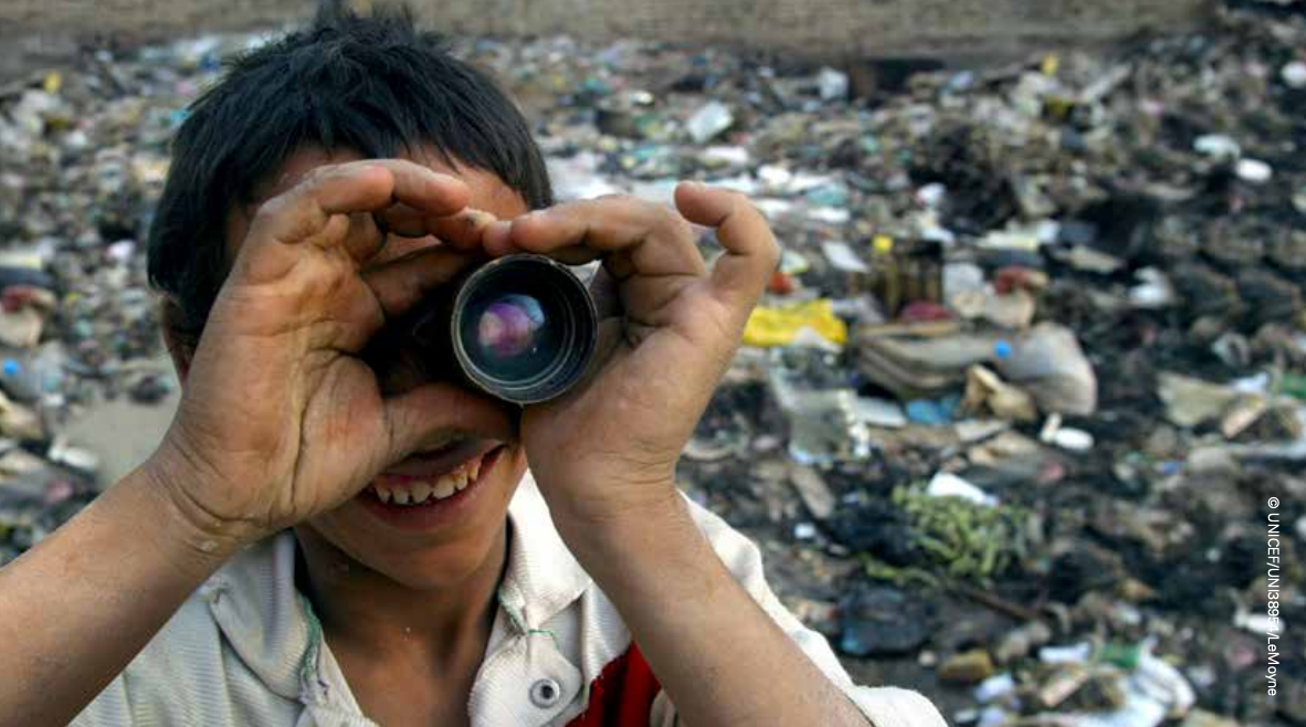 child looking through discarded camera lens