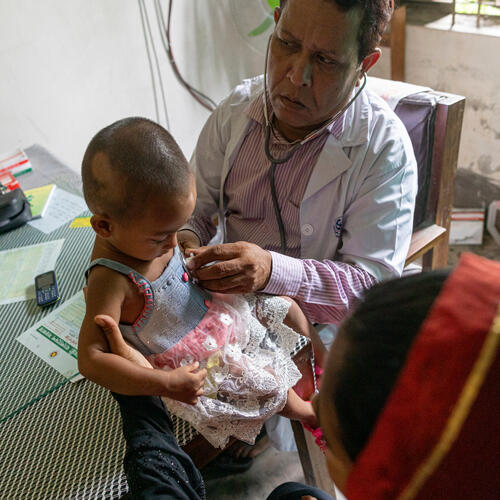 On 27 June 2019, Adriahok Naushin, 1, is steadied by her mother (right), Mariam Akhter, 23, as she is examined by Dr. Mosharraf Hossain, Sub-assistant Community Medical Officer, in the Baluakandie Health and Family Welfare Centre in the Gazaria sub-district of the Munshiganj district near Dhaka, Bangladesh. Dr. Hossain is the only doctor at the Centre, which offers free, government-supported medical treatment three days a week to the local community.