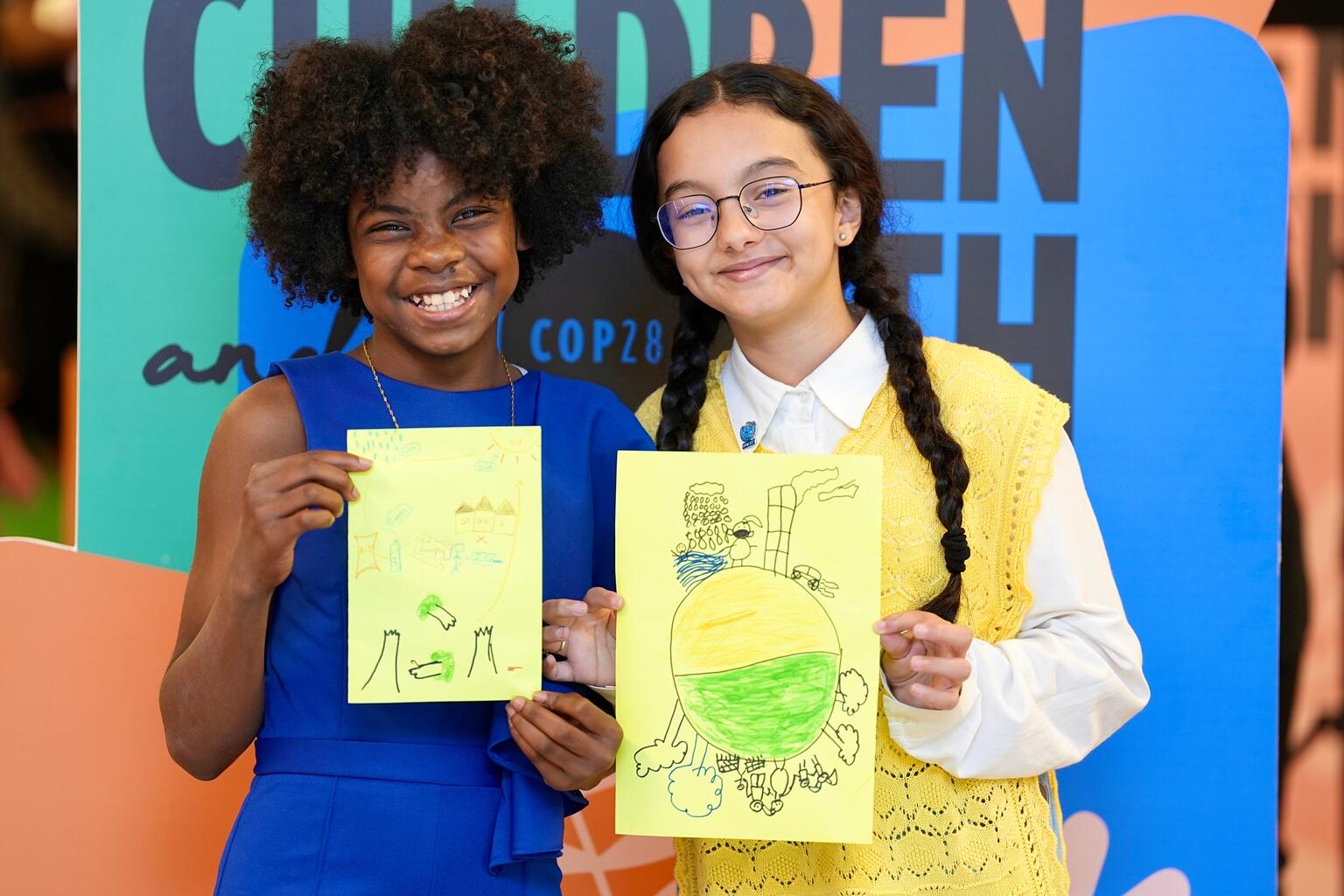 On 8 December 2023 at the UN Climate Change Conference (COP28) at Expo City Dubai in the United Arab Emirates, Lova Renee, 13-year-old UNICEF Youth Advocate from Madagascar, and Revan Ahmed, 13-year-old UNICEF Youth Advocate from Libya, pose for a photo with their drawings.