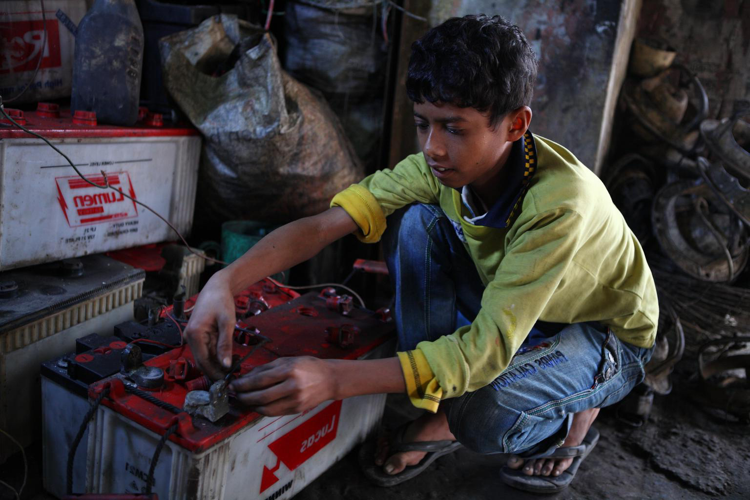 Boy working on lead acid batteries without protection