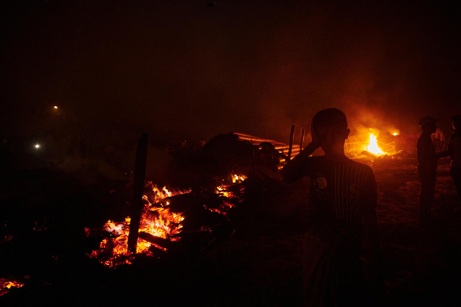 On 5 March 2023, at the centre of a dark and smoke-filled picture, a child can be seen amidst the burning fire and debris as refugees sift through the ruins of Balukhali refugee camp in Ukhia, Bangladesh.