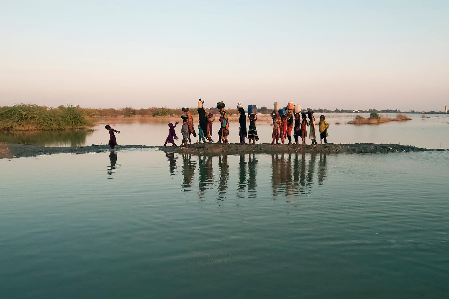 Women and girls walking with their buckets to fetch water in the inundated region of Geokaloi village in the Southern Pakistani province of Sindh.